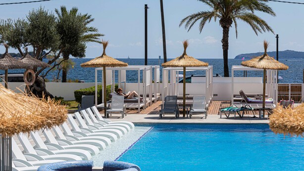 Zona de piscina con sillas de descanso, un jacuzzi y sombrillas.