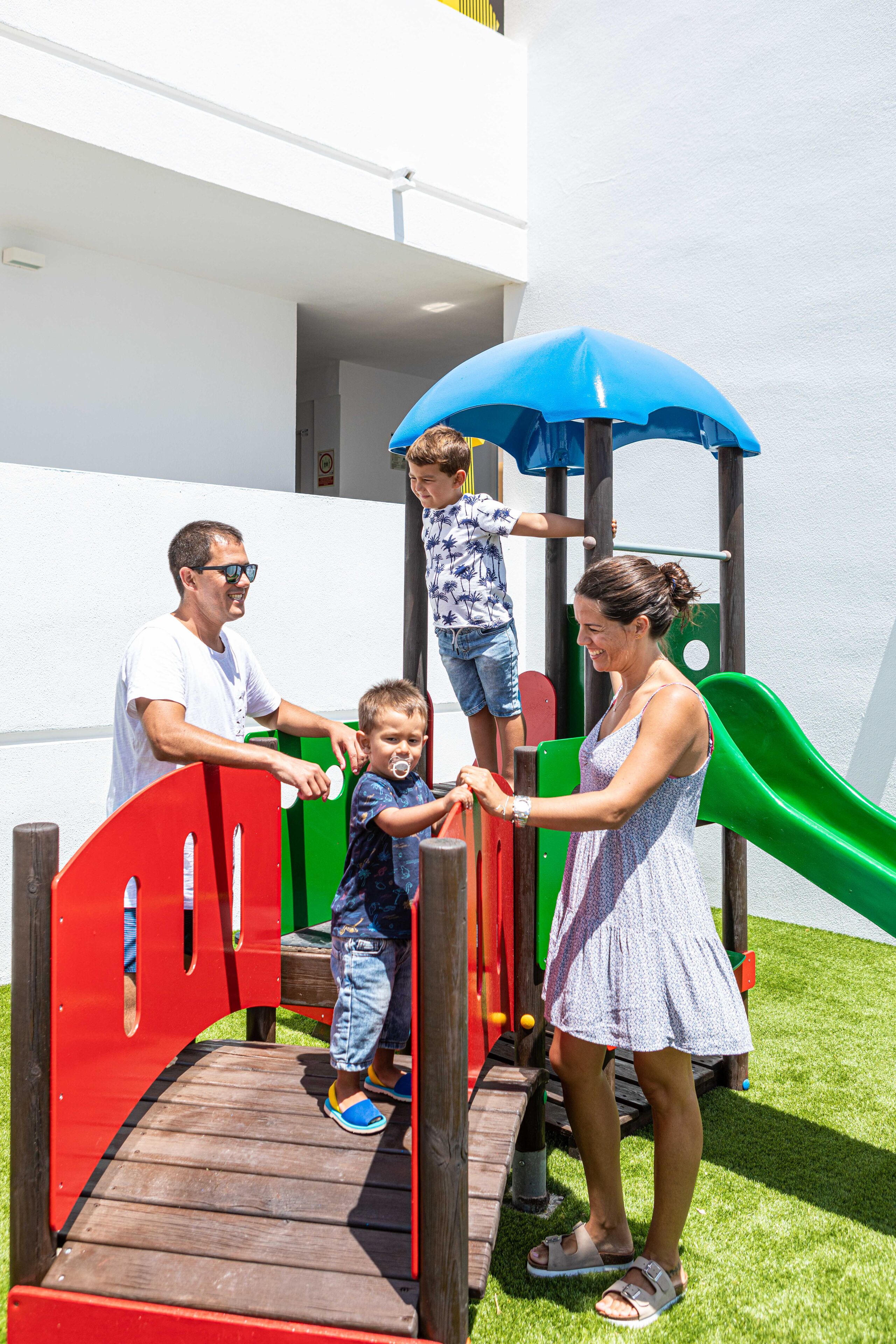 A playground with a slide, climbing area, and a red and green play structure.