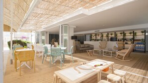 Un amplio espacio al aire libre con piso de madera, mesas, sillas y diversas opciones de asiento.