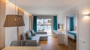 Habitación de hotel moderna con comedor, sofá, escritorio y vista a la piscina.