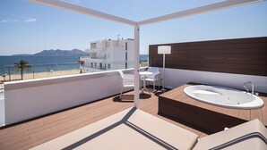 Un balcón con piso de madera, una bañera blanca y un juego de mesa y silla blancos.