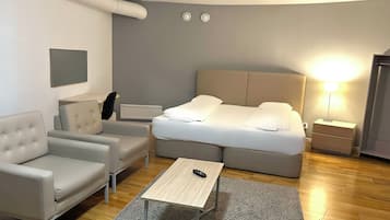 Una habitación de hotel moderna con cama, sofá, una mesita y una mesita de noche.