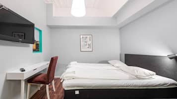 Un dormitorio moderno con una cama, un escritorio, una silla y un televisor montado en la pared.