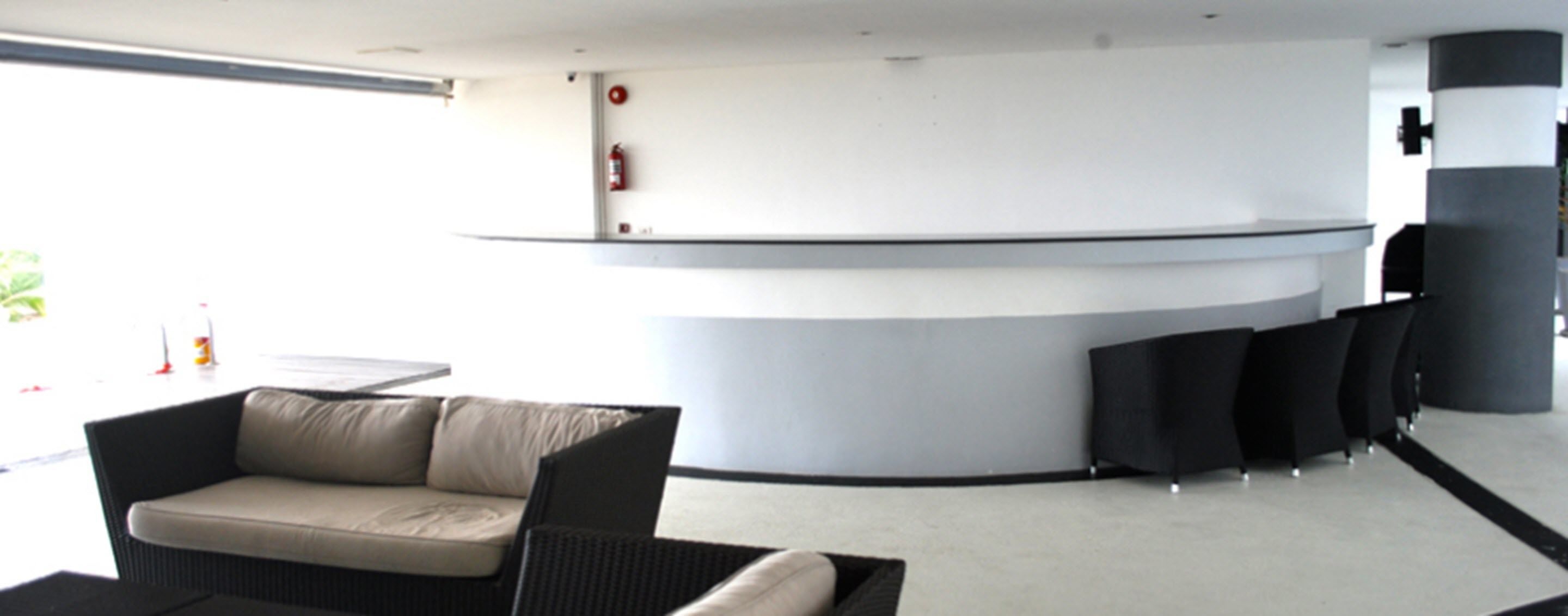 Et moderne receptionsområde med en buet disk, en sofa og en sort stol.