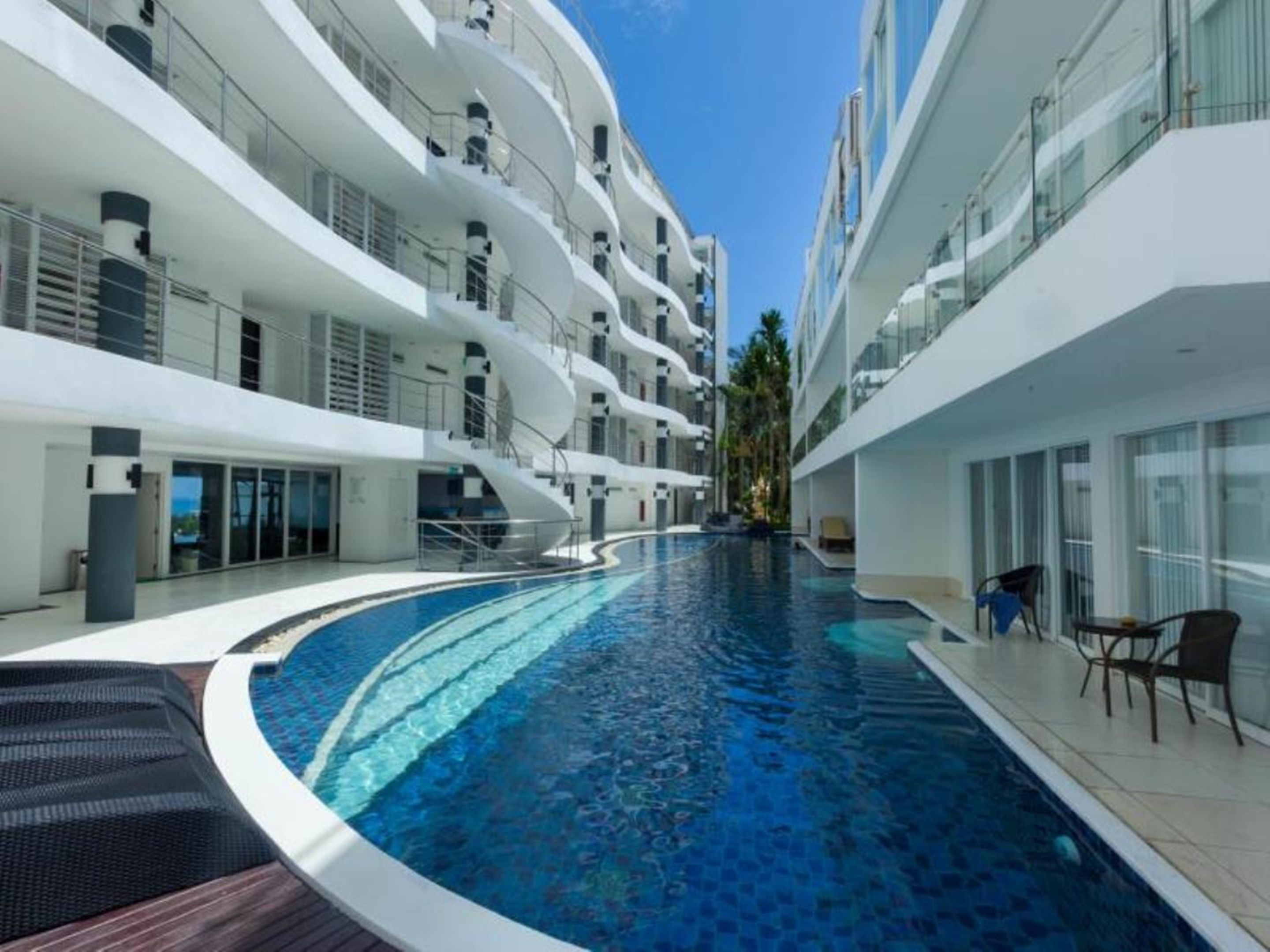 A modern hotel with a central swimming pool, multiple balconies, and a clean, contemporary design.