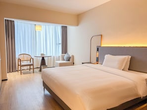 Une chambre d’hôtel avec un grand lit, un bureau, une chaise et une fenêtre avec des rideaux.