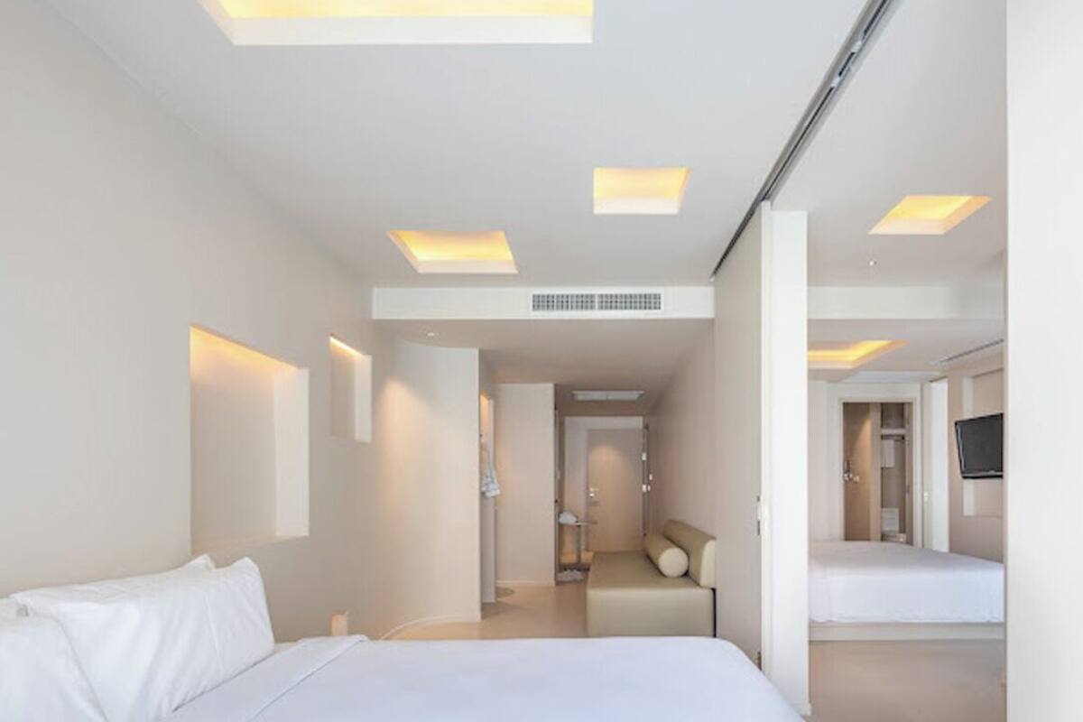 A modern hotel room with a large bed, a sofa, and a TV.