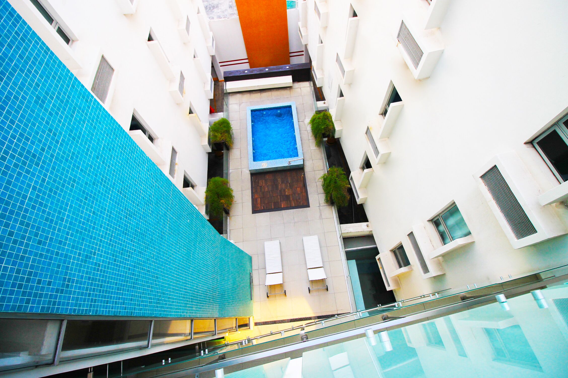 A modern building with a swimming pool, multiple balconies, and a blue-tiled section.