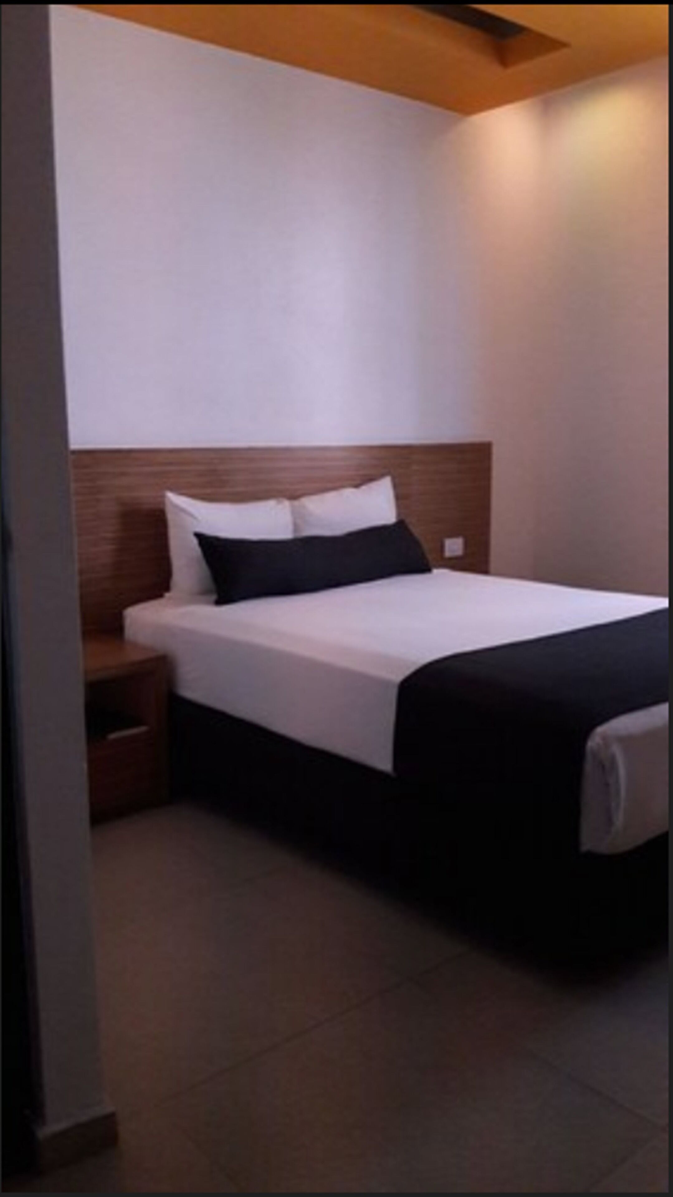 A hotel room with a bed, a nightstand, and a wooden headboard.
