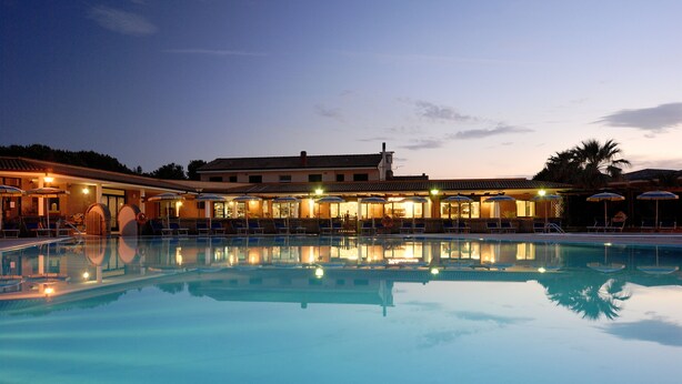 A swimming pool with a reflection of buildings and palm trees. - La Cecinella (Cecina)