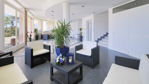 A modern lobby with wicker furniture, a potted plant, and a small table with a candle. - La Cecinella (Cecina)