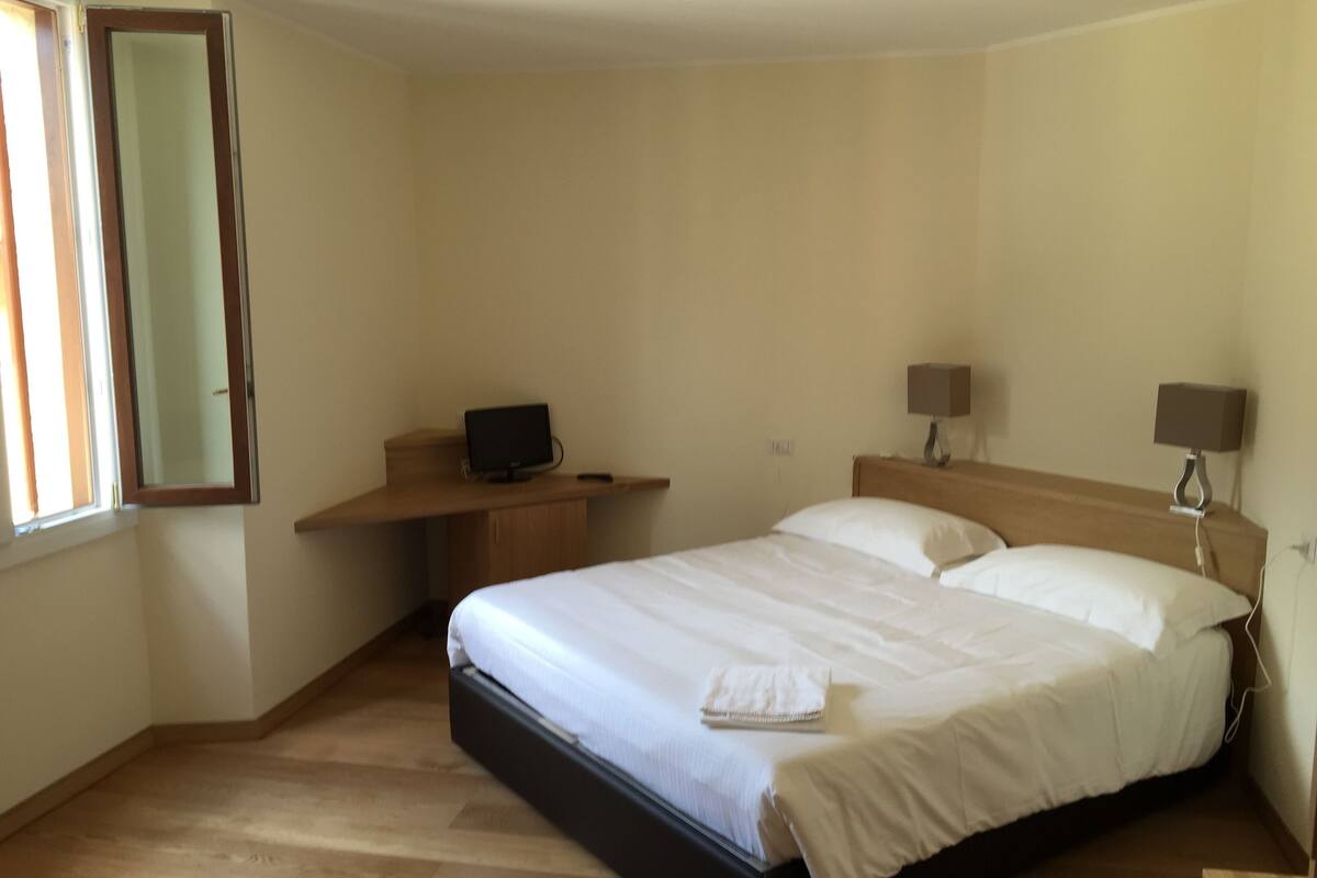 Une chambre à coucher avec un lit, un bureau avec un ordinateur et deux lampes de chevet.