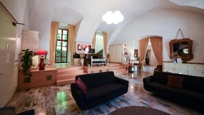 A spacious living area with a high ceiling, a staircase leading to an upper floor, and a cozy seating area with sofas. - Trieste (Morbegno)