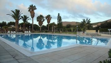 Una piscina al aire libre de temporada, tumbonas