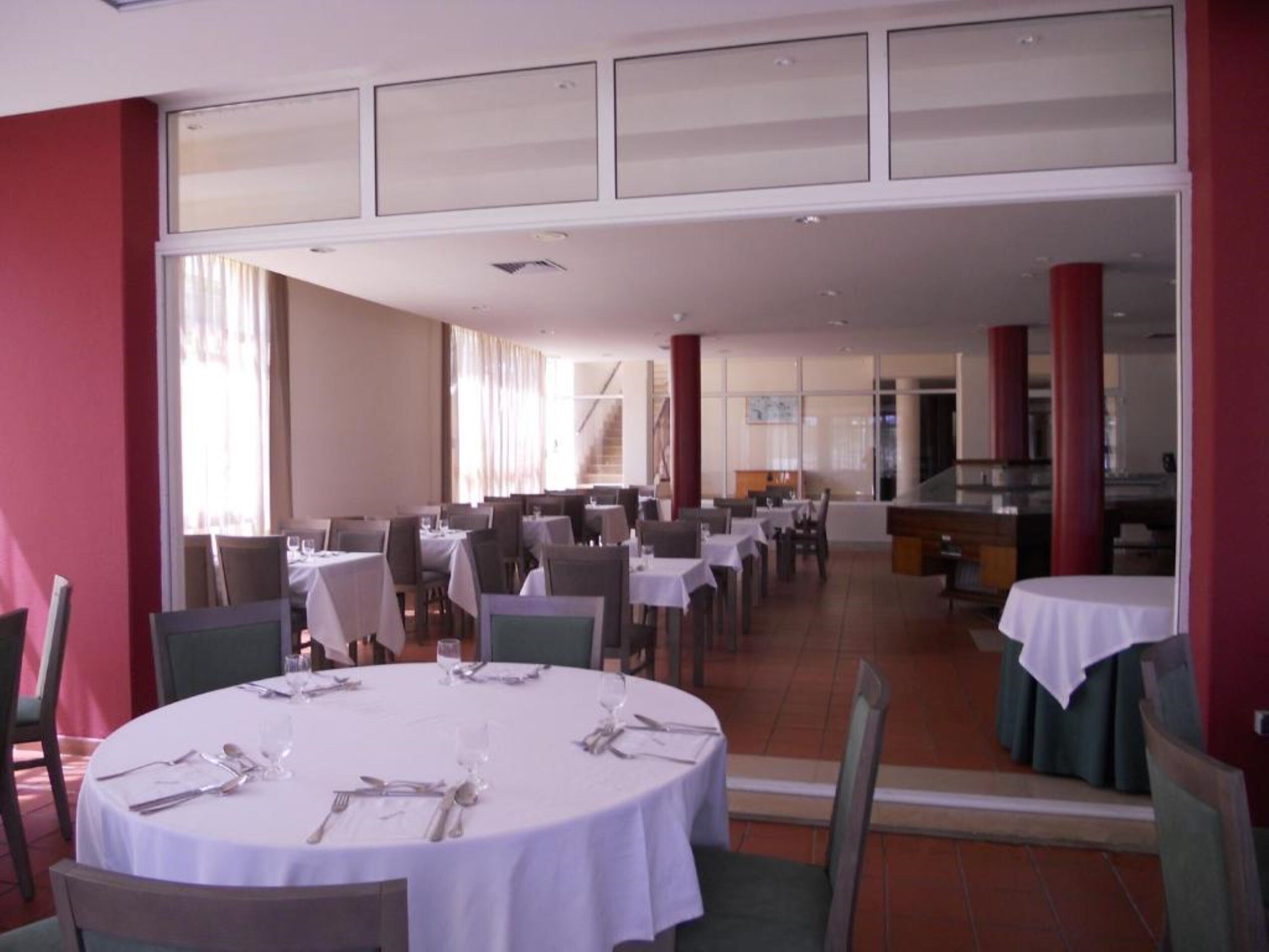 Un vaste espace dédié à la salle à manger, avec des tables rondes, des chaises et une vue sur l’intérieur.