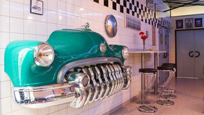 Exhibición de autos antiguos con detalles cromados y un patrón de pared a cuadros.