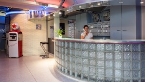 Zona de recepción con un mostrador de vidrio, un reloj y un letrero para una máquina de café.