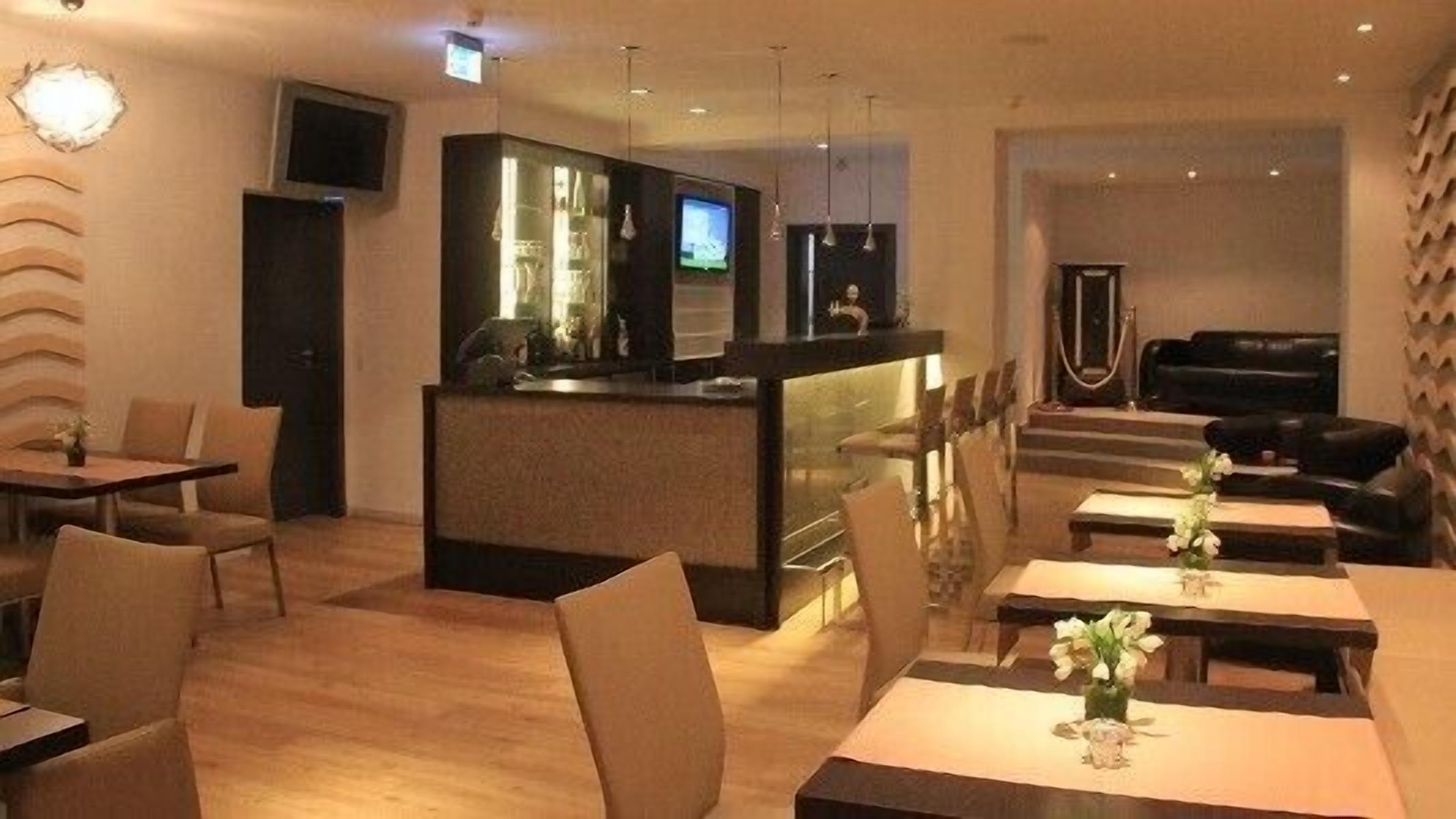 A modern restaurant with a bar area, seating arrangements, and a television screen.