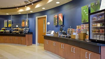 A modern breakfast area with a curved counter, a refrigerator with beverages, and a variety of food items.