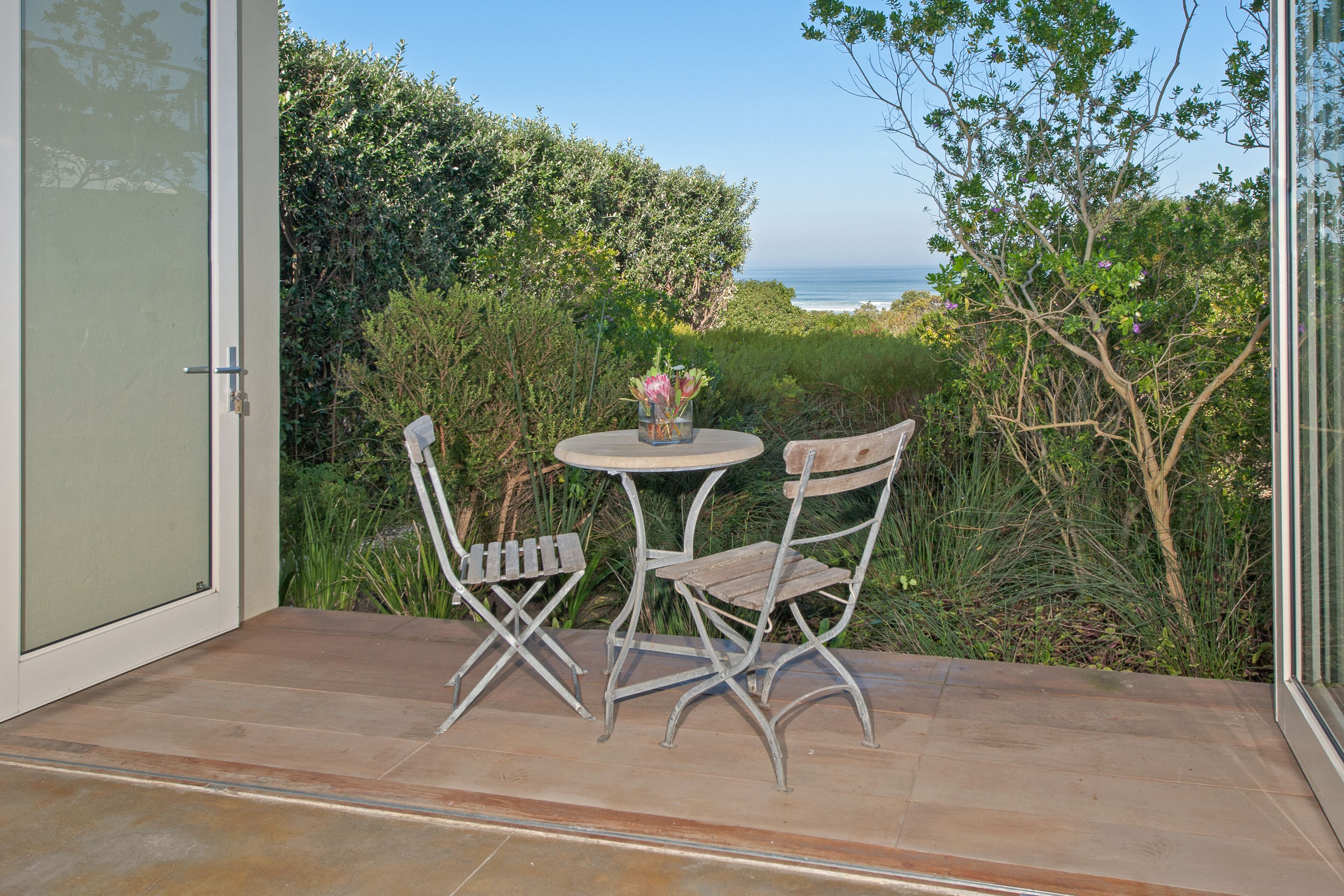 A patio with two chairs and a table, overlooking a coastal view.
