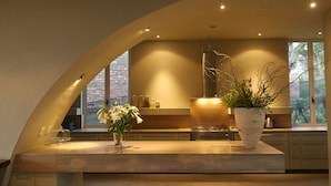 A modern kitchen with a curved ceiling, a large window, and a potted plant on the counter.