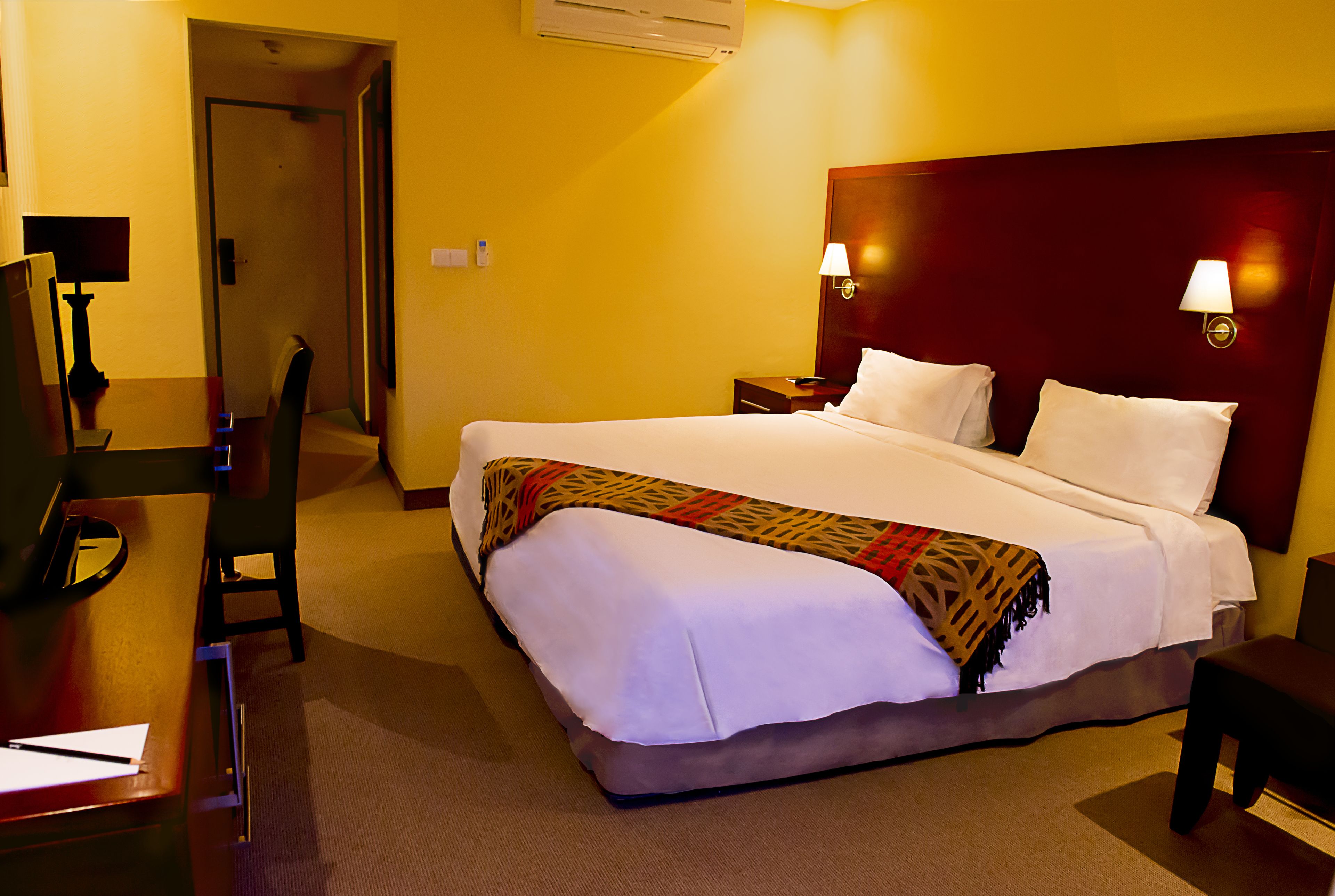 A hotel room with a bed, desk, chair, and nightstand.