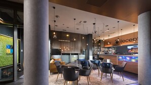 Uma área de recepção moderna com bar, assentos e uma parede verde.