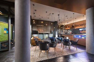 A modern reception area with a bar, seating, and a green wall.