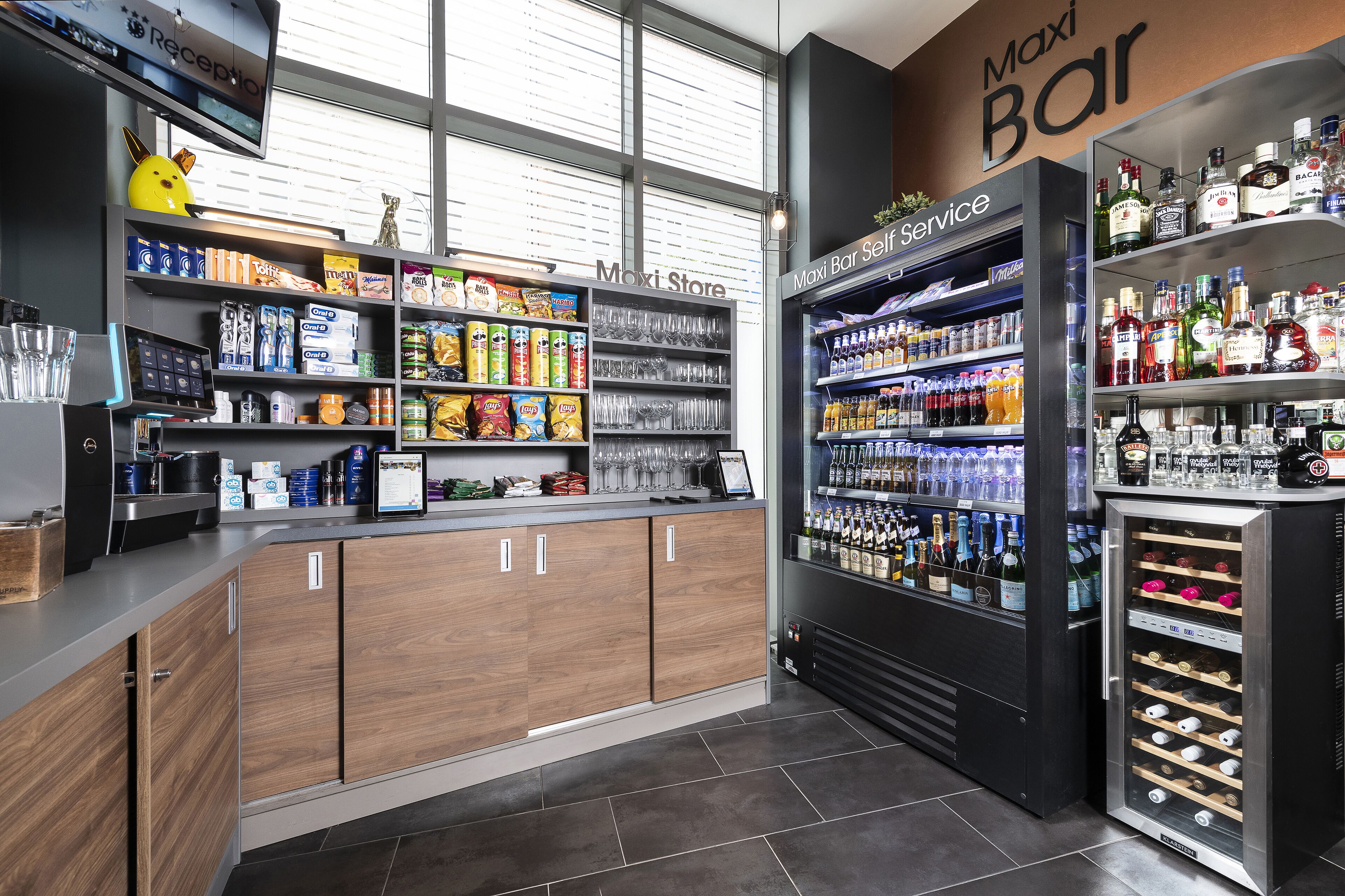 Un espace bar moderne doté d’un coin libre-service, d’une variété de collations et d’un réfrigérateur à vin.