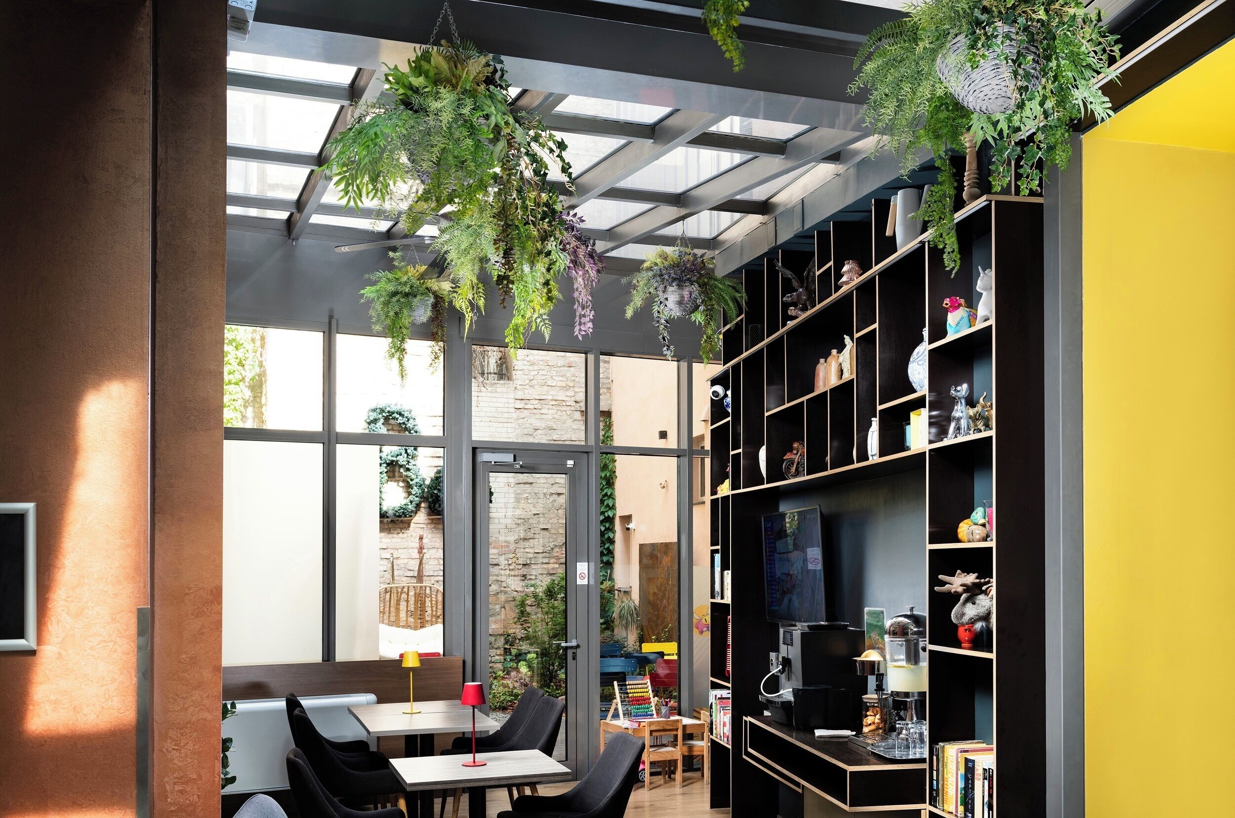 A modern interior with a dining area, a coffee station, and a bookshelf filled with decorative items.