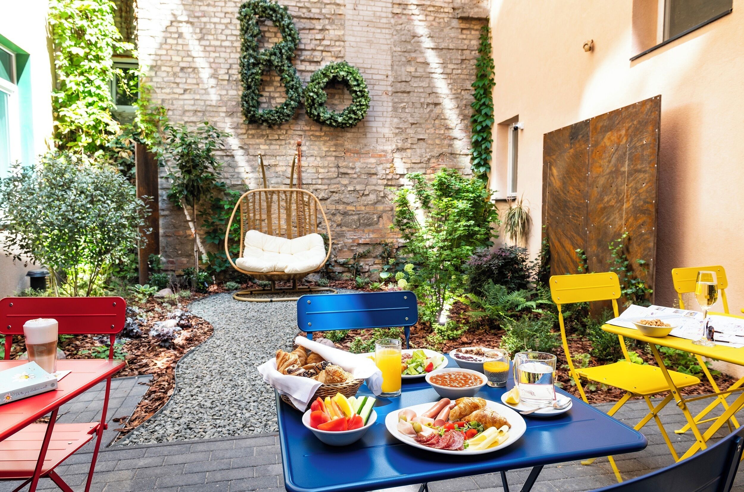 An outdoor dining area with a brick wall, greenery, and a wicker chair.