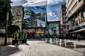 A modern urban square with a central water feature, surrounded by contemporary buildings with commercial signage. - Bo18 Hotel Superior (Budapest)