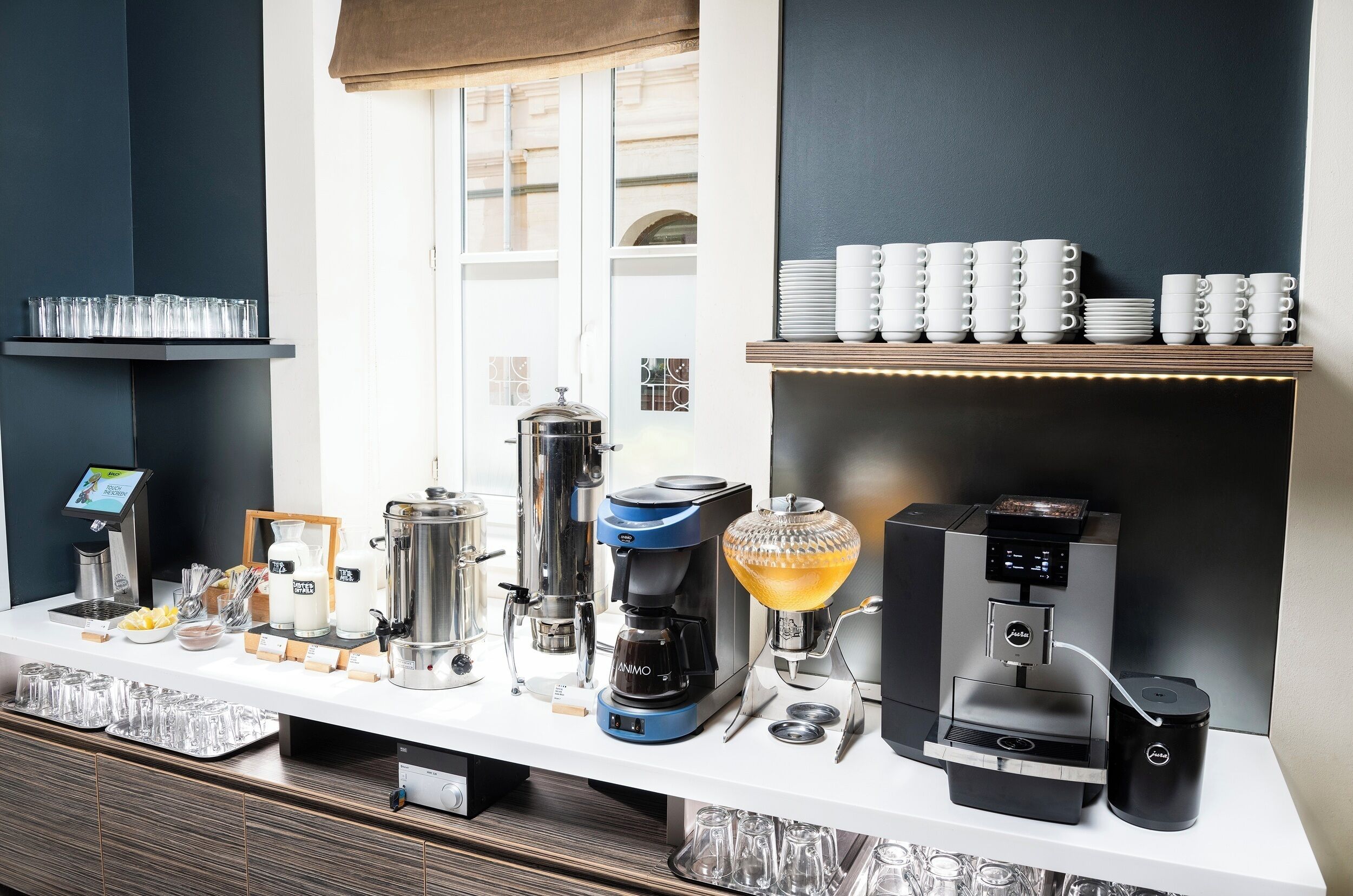 A coffee station with various brewing equipment and a selection of cups and glasses.