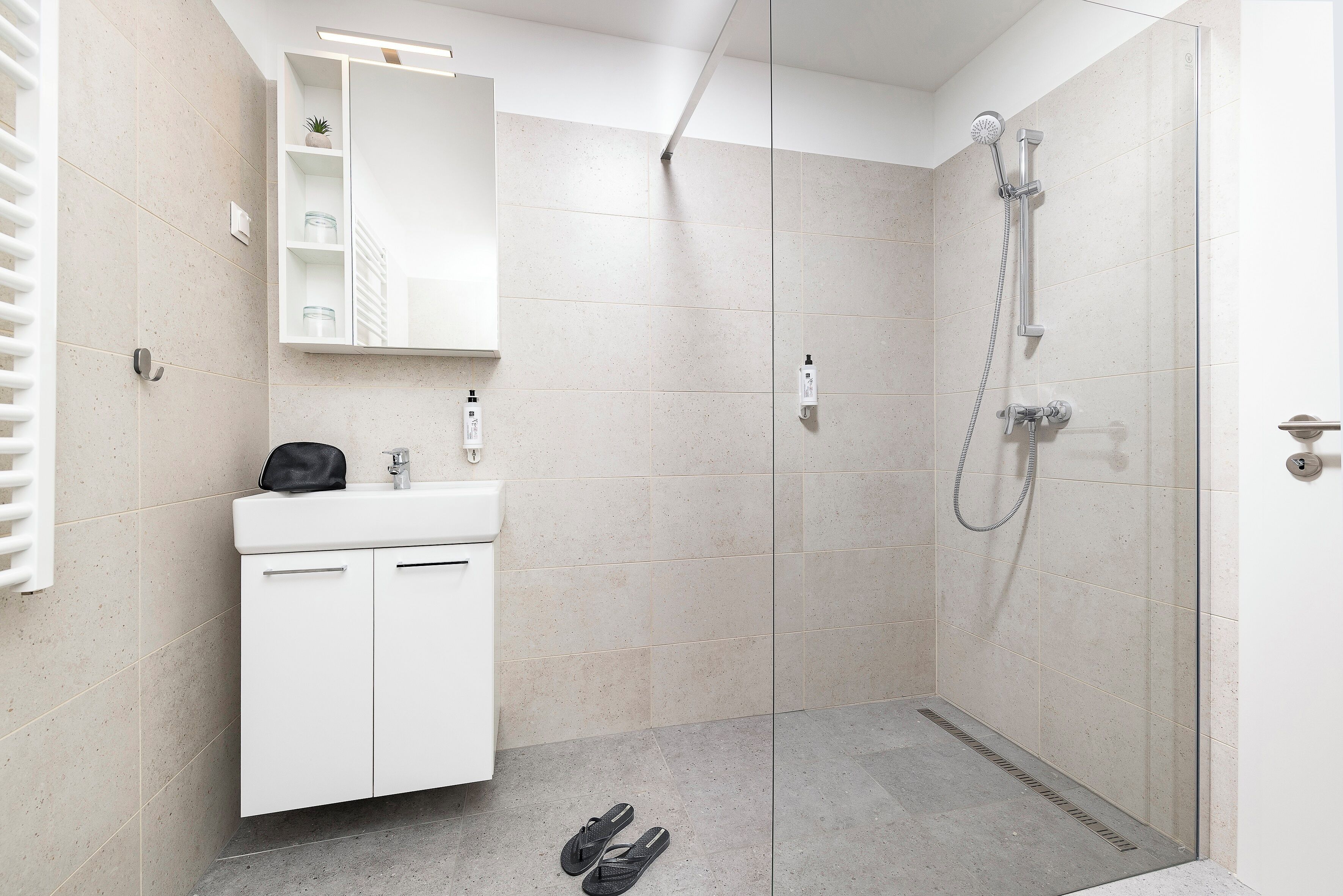 Een moderne badkamer met een douche, wastafel en spiegel.