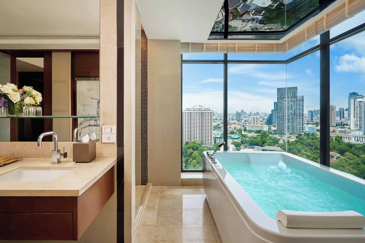 A modern bathroom with a large window, a bathtub, and a sink.