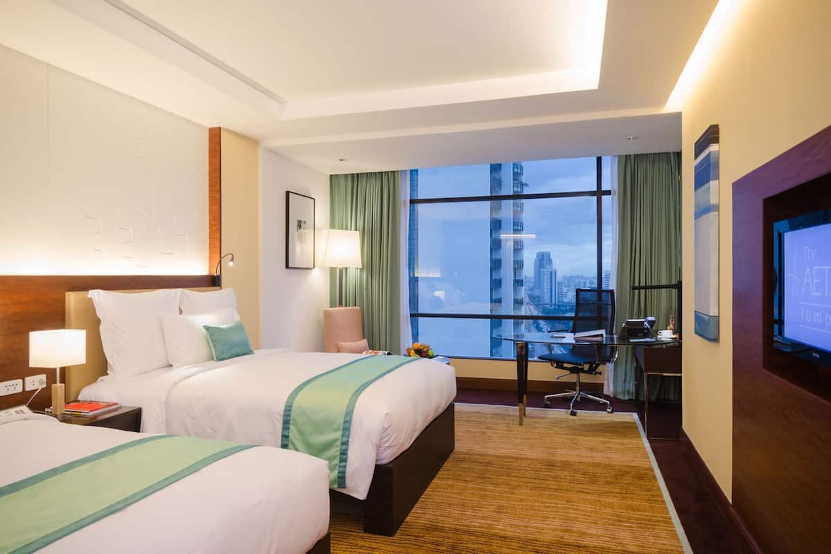 A hotel room with a bed, desk, TV, and a city view.