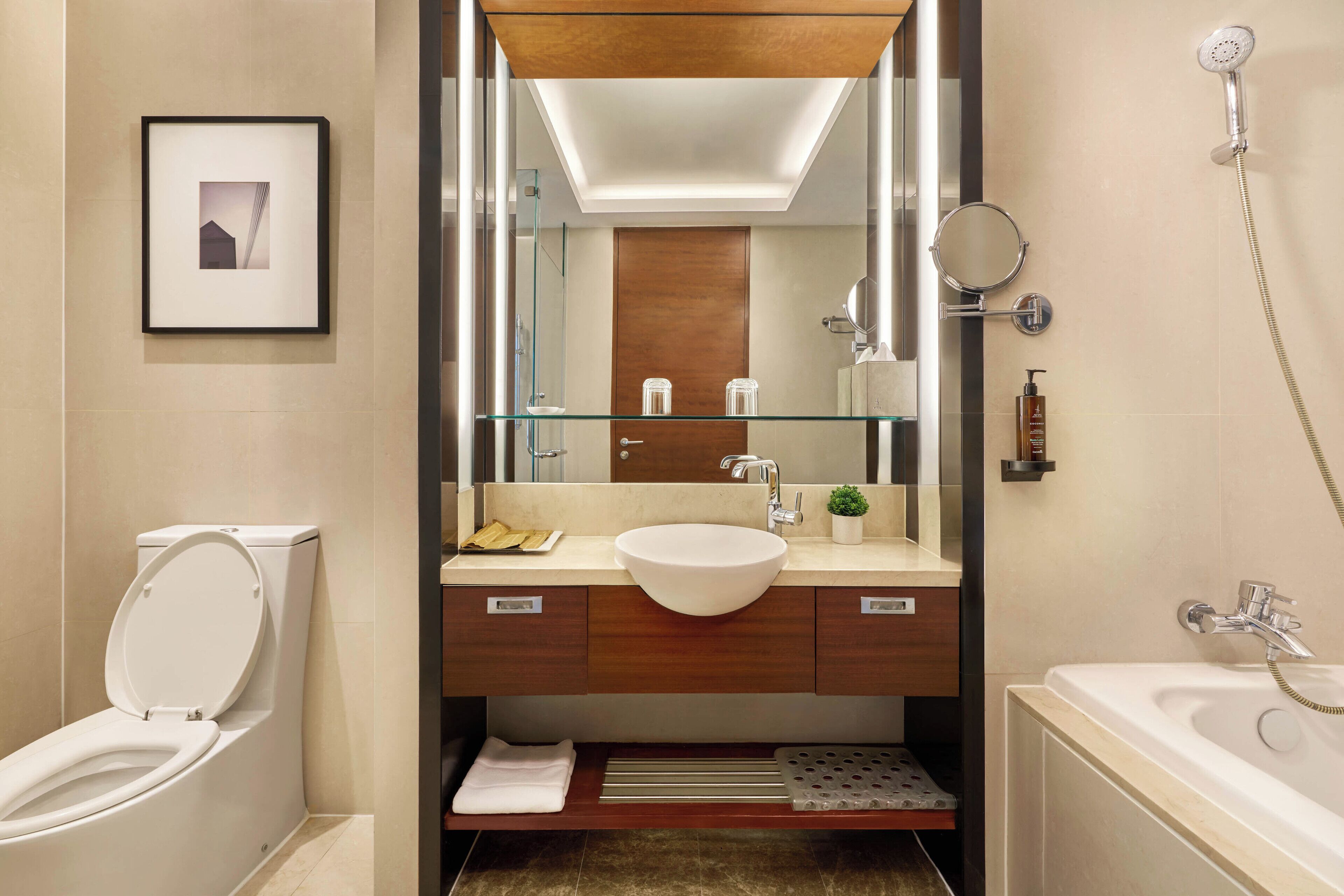 Un baño moderno con inodoro blanco, lavabo grande, espejo y ducha.