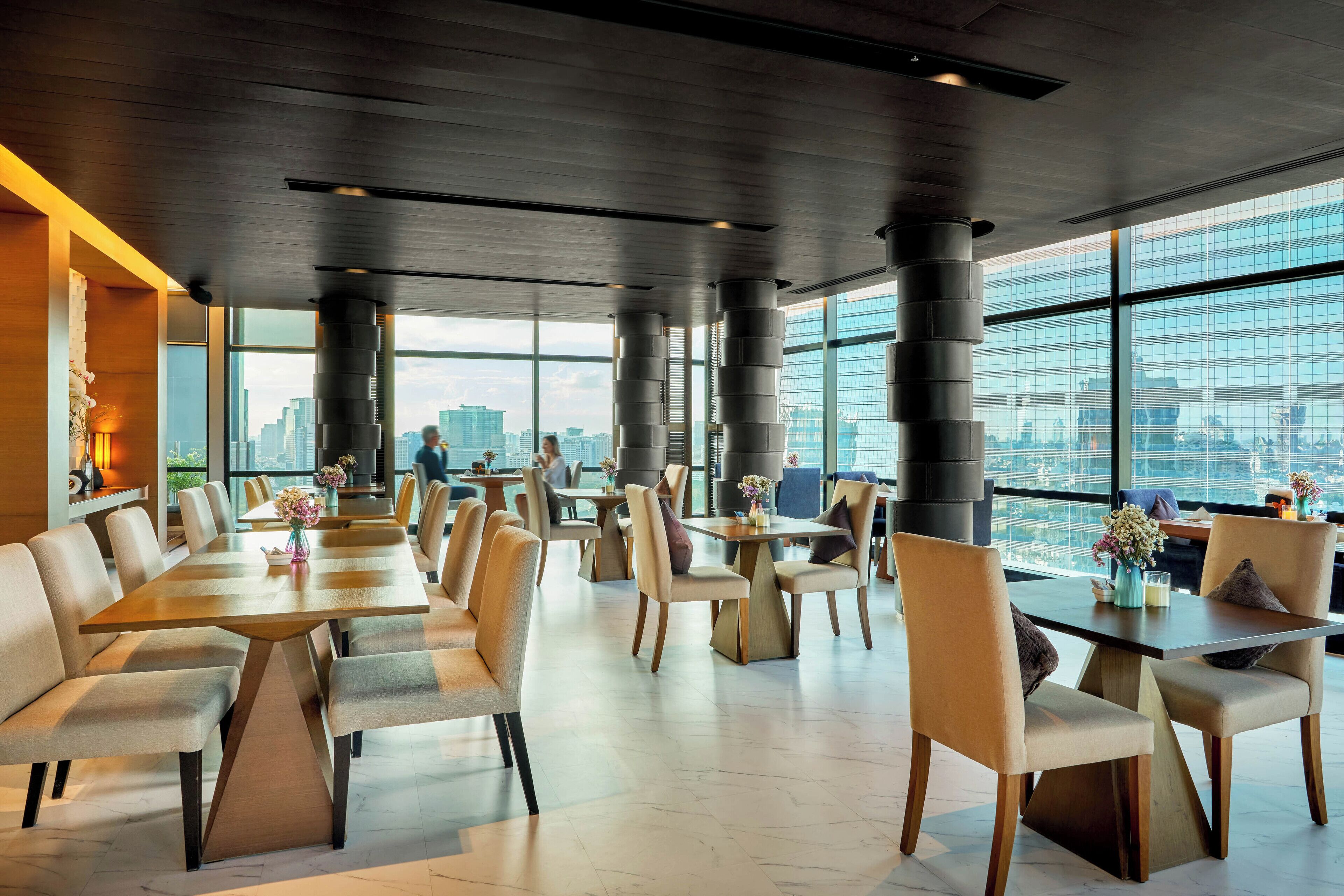 Un comedor moderno con techos altos, ventanas amplias y vista a la ciudad.