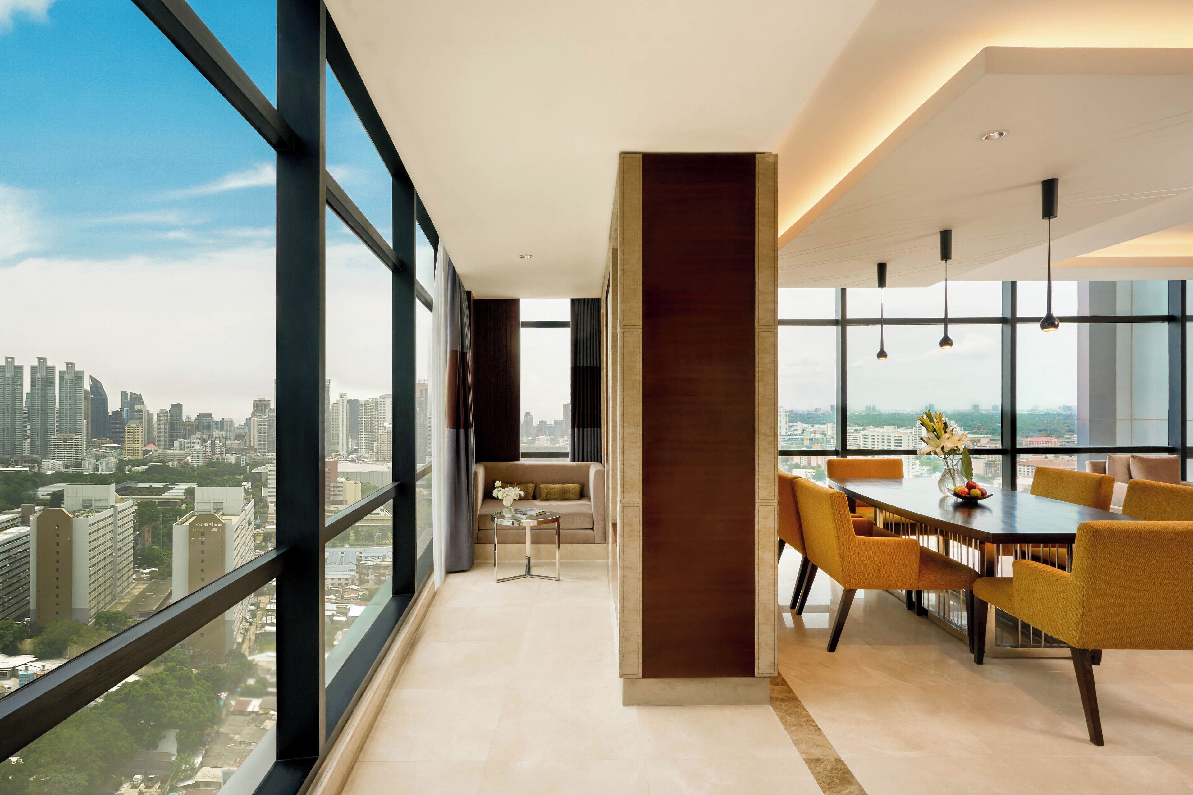 Um interior moderno com área de jantar, um sofá e vista para a cidade.