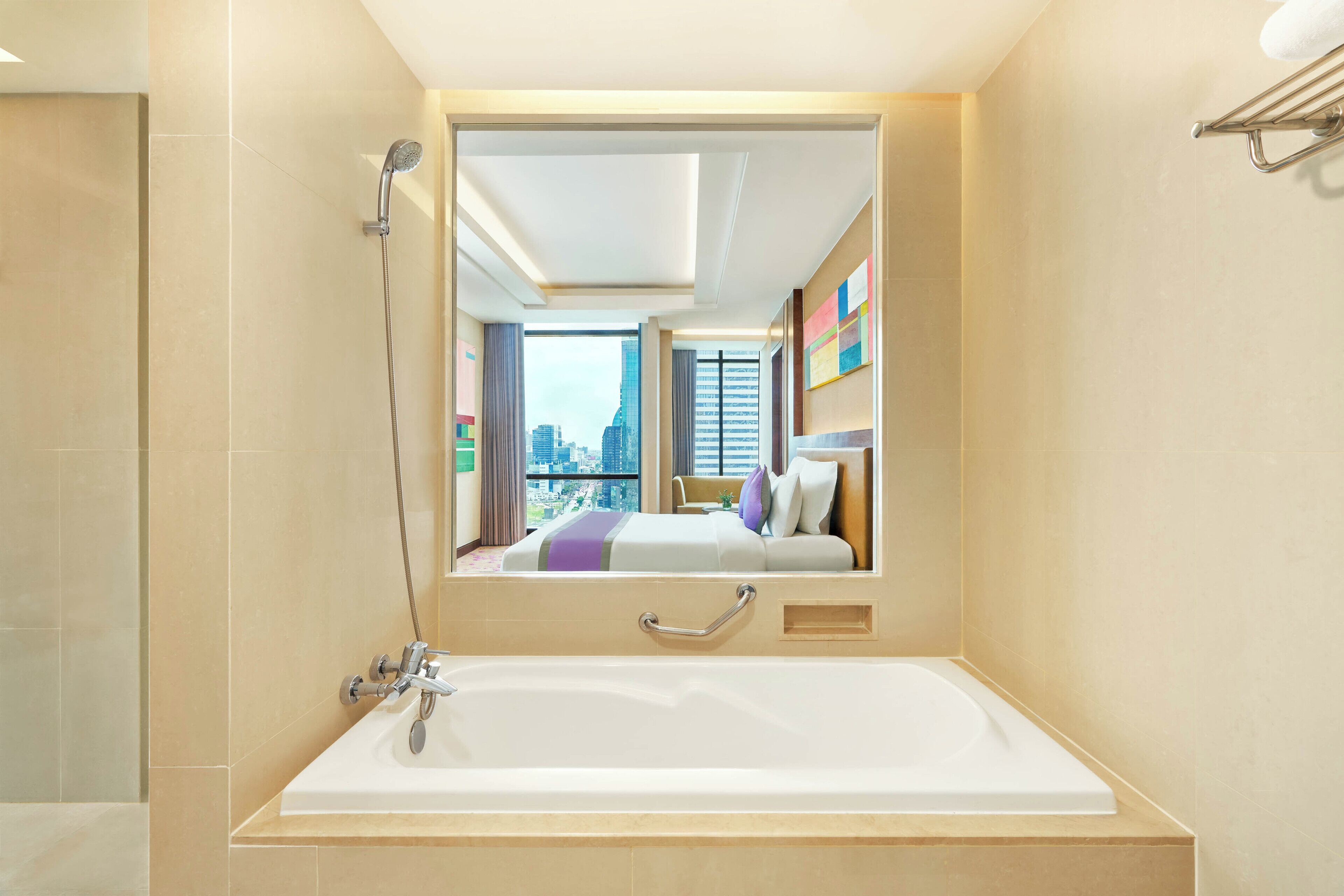 Ein modernes Badezimmer mit einer großen Badewanne, einer Duschbrause und einem Spiegel, der den Blick auf eine Stadtlandschaft reflektiert.