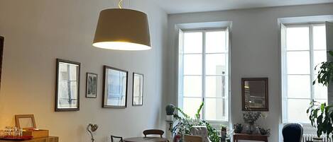 A spacious dining area with a long wooden table, surrounded by chairs, and a hanging light fixture.
