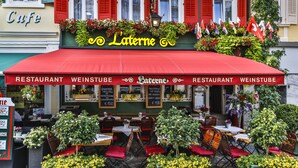 A restaurant with outdoor seating, red awnings, and flags. - Hotel Laterne (Baden-Baden)