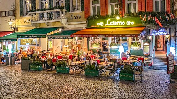 A European-style building with a cafe and restaurant on the ground floor, featuring outdoor seating and a cobblestone street. - Hotel Laterne (Baden-Baden)