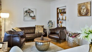 A living room with a brown leather sofa, a round coffee table, and a bookshelf. - Hotel Laterne (Baden-Baden)
