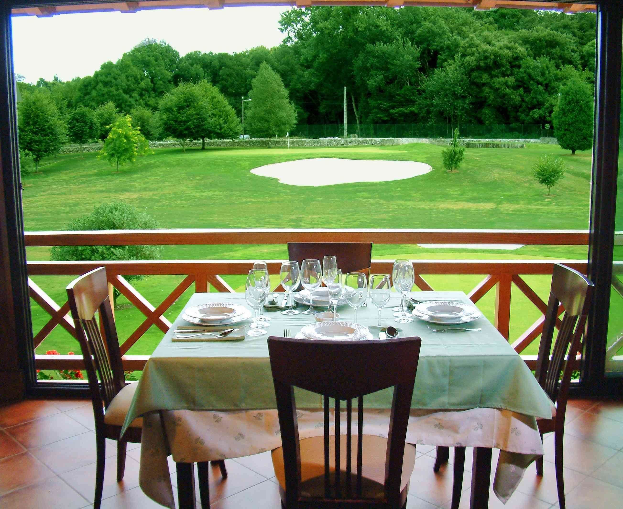 A dining table set for four with a view of a golf course.