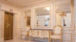 Ein luxuriöser Raum mit aufwendigen Möbeln in Gold und Weiß, einem großen Spiegel und einer Chandeliebre.