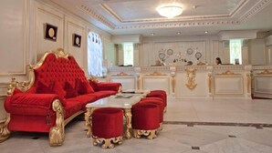 Ein luxuriöses Zimmer mit einem roten Sofa, passenden Hocker, einem Marmor-Couchtisch und einem weißen Empfangstresen.