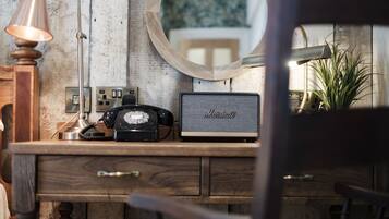 A wooden desk with a vintage telephone, a Marshall speaker, and a lamp.