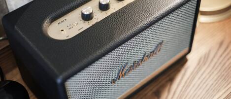 Un amplificador Marshall negro con cuatro perillas y una rejilla de altavoz sobre una superficie de madera.