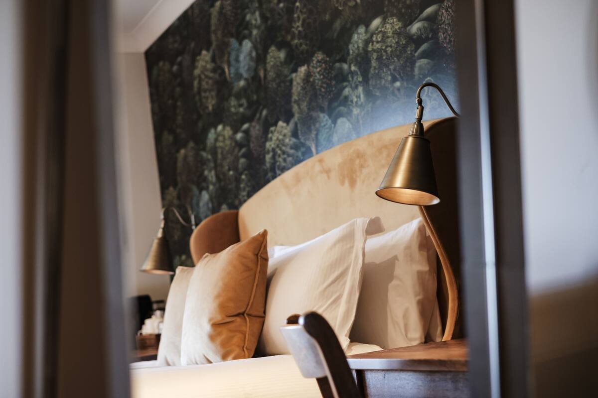 A modern bedroom with a large bed, a headboard, and a bedside lamp.